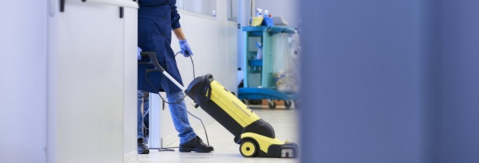Schoonmaakmedewerker reinigt een vloer met een schrobmachine